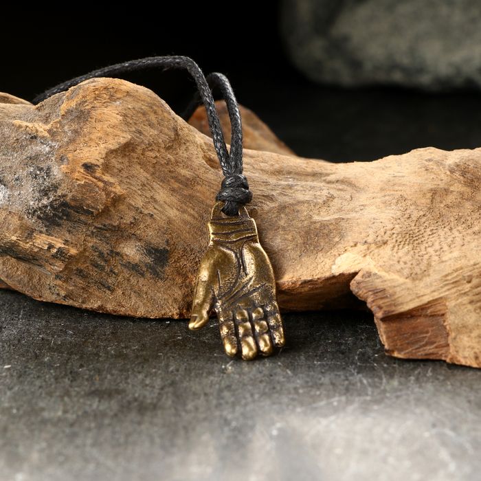 старинный металлический амулет на ладони