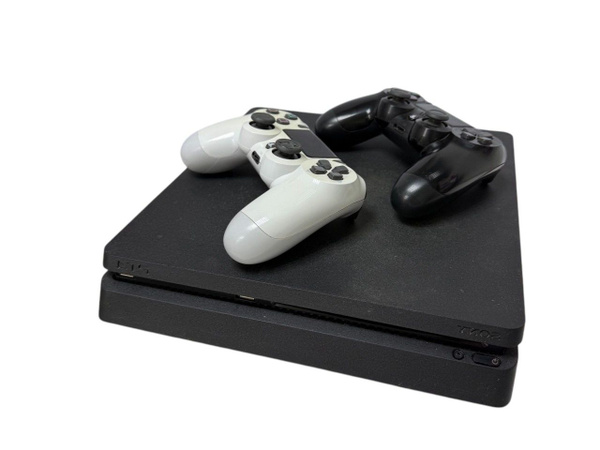 игровая приставка и два геймпада на диване