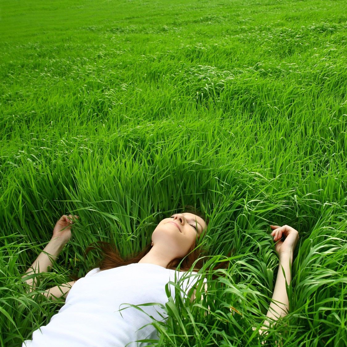 девушка лежит на траве. красивая девушка с наушниками. человек надевает наушник. спокойная музыка для отдыха. человек в наушниках на природе.