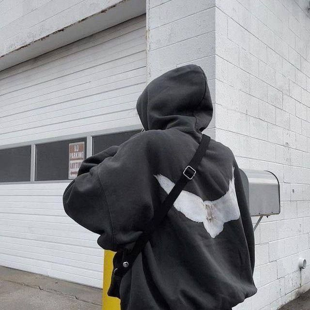 человек в худи с вышивкой на спине на городской улице